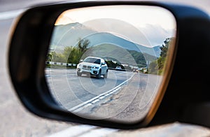 View through the rearview mirror of the car on the movement of cars on a highway