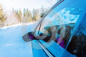 View of the rearview mirror of a moving car on a snowy, winter surface