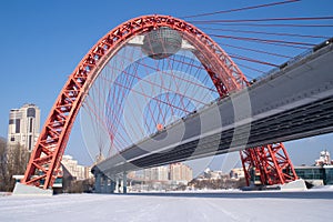 View of red arc bridge on frozen river and houses