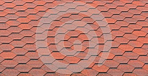 View of red bituminous roof tiles. Asphalt shingles roofing construction. Template for roofers