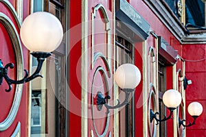 View on red building with white glass ball lamps in row - image