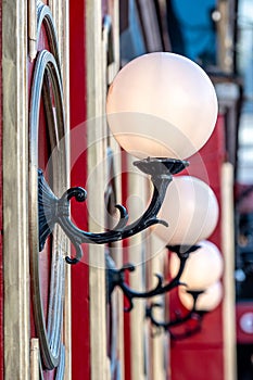 View on red building with white glass ball lamps in row - image