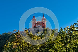 View of the red Calvary Banska Stiavnica under a blue sky with forest in foreground