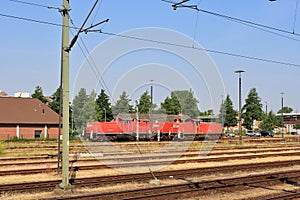 View of red locomotive and multiple train tracks from platform at Itzehoe train station in summer