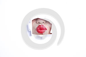 View of red puckered lips through paper hole