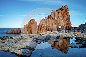 view of the red rocks of Arbatax with reflections in tidal pools in the foreground