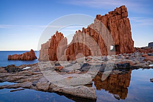 view of the red rocks of Arbatax with reflections in tidal pools in the foreground