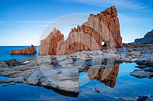 view of the red rocks of Arbatax with reflections in tidal pools in the foreground