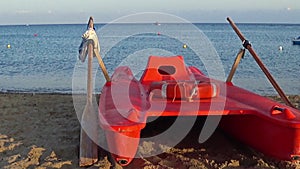 View of a red rowing catamaran of the lifeguard on the seashore. 4K