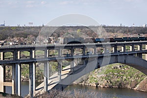 View of the reinforced concrete two-level arched bridge. Freight train rides across the bridge.