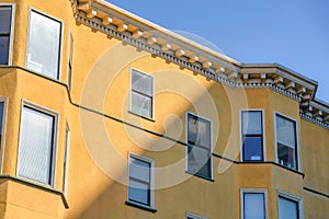 View of a residential building with yellow stucco wall and decorative eaves in San Francisco, CA