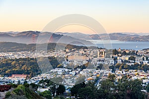View of a residential district of San Francisco at sunset. The Golden Gate Bridge and the bay are in background.