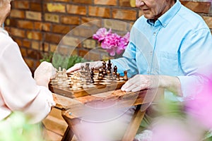 View of retired couple playing chess on wooden table
