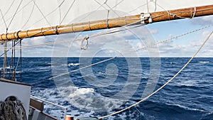 view from a retro style sailing schooner during the passage of the Drake Strait, wooden boat boom, lots of ropes, large