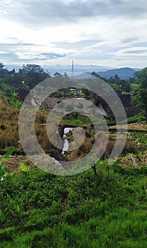 View of a rice field, houses and telecommunication towers from a distance and the blue sky