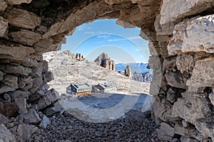 View of the rifugio Boe mountain hut through a stone window in the cairn. Dolomites, Italian Alps. Sella massif