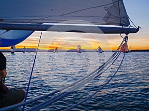 View through rigging to other yachts sailing at sunset
