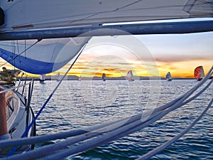 View through rigging to other yachts sailing at sunset