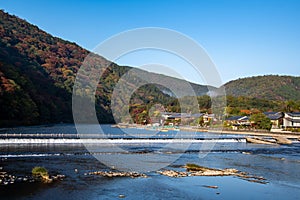 A view of the of the river and autumn colours of the surrounding mountains, seen from Togetsu-kyo bridge.