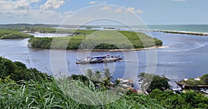 View of river and blue sea with boats and coastal vegetation on the beach in Santa Cruz CabrÃÂ¡lia - Bahia - Brazil. photo