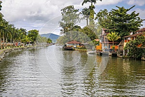 View of river Pereque-Acu with houses and vegetation and rainforest mountain in Unesco World Heritage town Paraty, Brazil