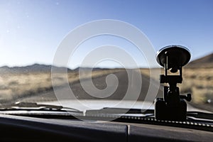 View of the road ahead through a windshield next to an action camera with the dash close up defocused