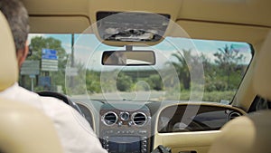 View on road from backseat of luxury vehicle, business driver behind the wheel