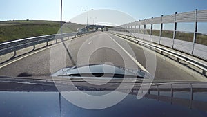 View of road on Crimean bridge from moving blue car. Go pro is on roof of automobile. Fish eye