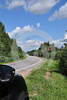 View of the road and the parked car on the side of the road. Road sign