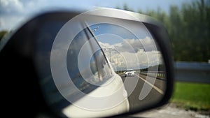 View of the road in the rearview mirror of a car on summer straight road - wedding motorcade