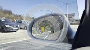 View of the road in the rearview mirror of a car at sunset