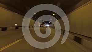 View of road tunnel with yellow light. Scene. Car leaves from long tunnel ahead of blinding white light of sun