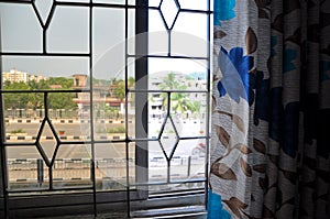 View of the road through the window and curtains on a sunny day