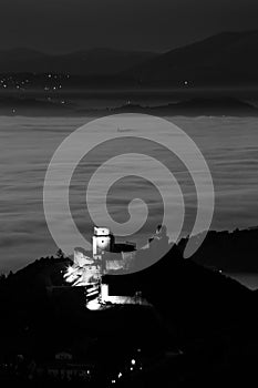 View of Rocca Maggiore Assisi Umbria Italy above a sea of fog at night, during Christmas 2023