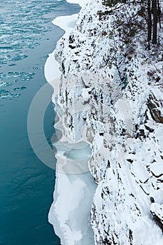 View of rocks, stones and ice in the river at winter. The trees and stones are covered with snow