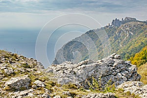 View of rocky mountainside on black sea with a peak on top