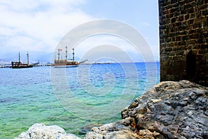 View from the rocky shore to the pleasure boats sailing at anchor in the city harbor Alanya, Turkey