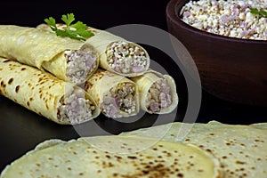 View of rolled pancakes with ham and egg with a black background