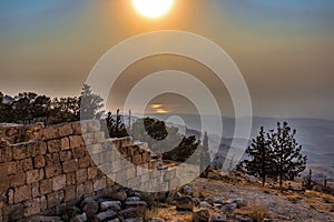 View of a rolling mountain landscape with trees and fog at sunset, called Mount Nebo in Jordan, where the Bible, God showed Moses