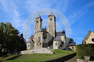 View on roman basilica from 11th century with two towers on green hill against blue sky in summer