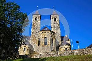 View on roman basilica and monastery from 11th century with two towers on green hill against blue summer sky - Sint Odilienberg,