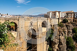 View of Ronda, Andalusian town situated atop spectacular deep gorge, with a massive stone bridge with arches, Spain