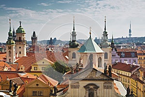 View of the roofs of Prague, with red tiled roofs and statues, spires and towers protruding