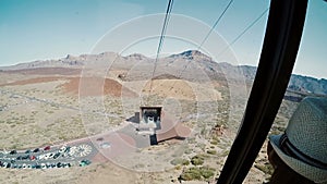 View from a ropeway cabin to mountains and station of departure. Cablecar moves up to the top of volcano.