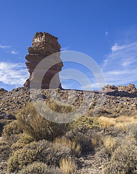 view on Roque Cinchado gods finger, famous rock formation in Roques de Garcia el teide national park with dry vegetation and