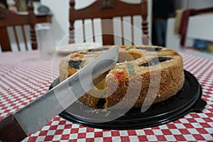 View of a Rosca de Reyes Epiphany Kings Cake on top of a red and white table cloth