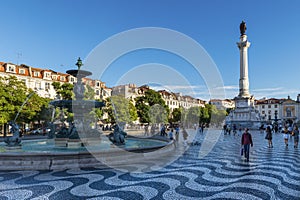 View of the Rossio Square with tourists walking by, in the pombaline downtown of the city of Lisbon