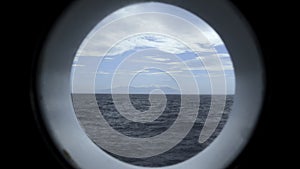 View from round deck window to sea. Clip. Beautiful seascape with mountain coast on horizon from round window. Sea