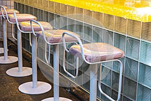 View of a row of bar stools that stand near a bar counter made of glass blocks. Concept interior, business, quarantine