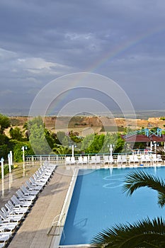 A view of a rural lansdcape, swiming pool and rainbowd